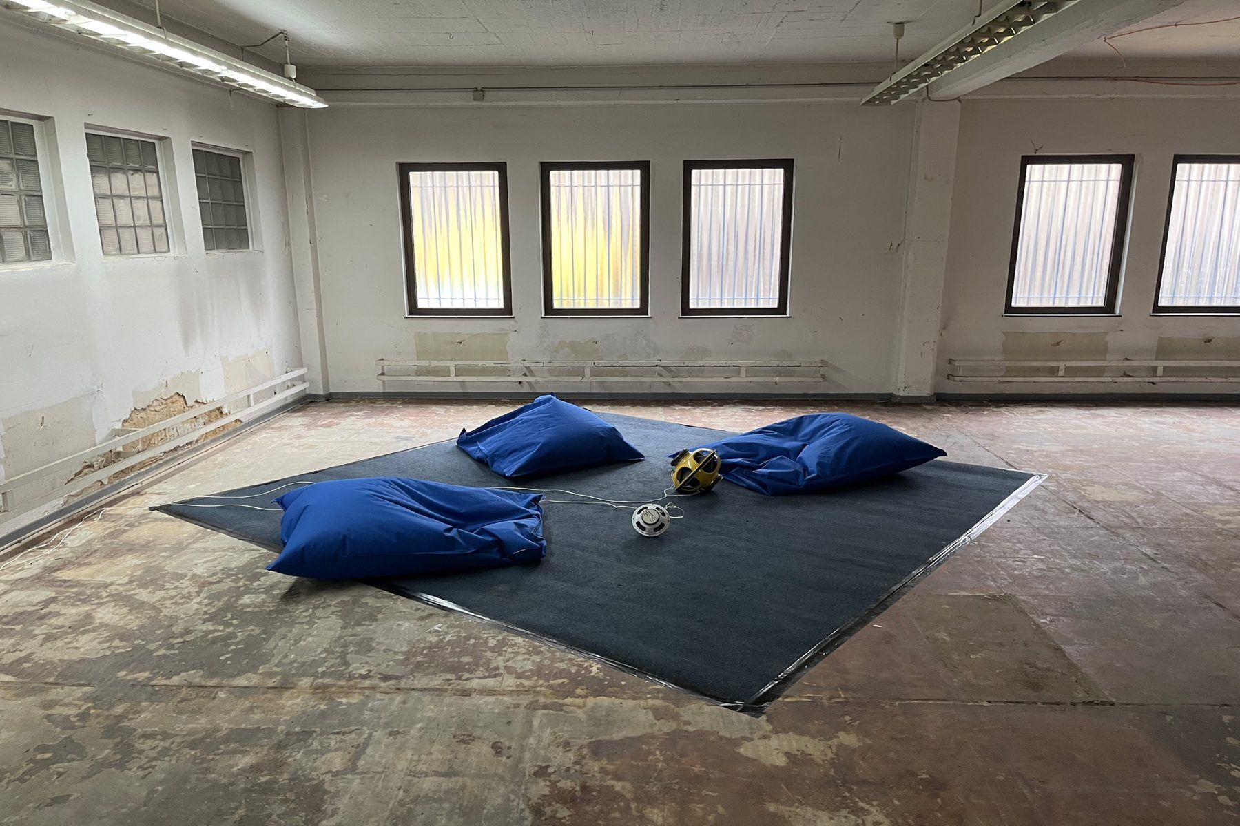 Installation view at RANGE Festival 2024: carpet, blue beanbags, two spheres