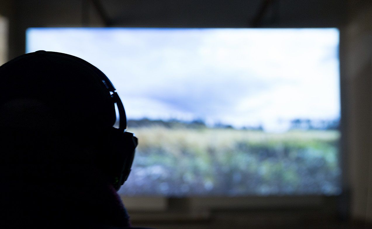 Silhouette einer Person mit Kopfhörern vor der Projektion einer Landschaft