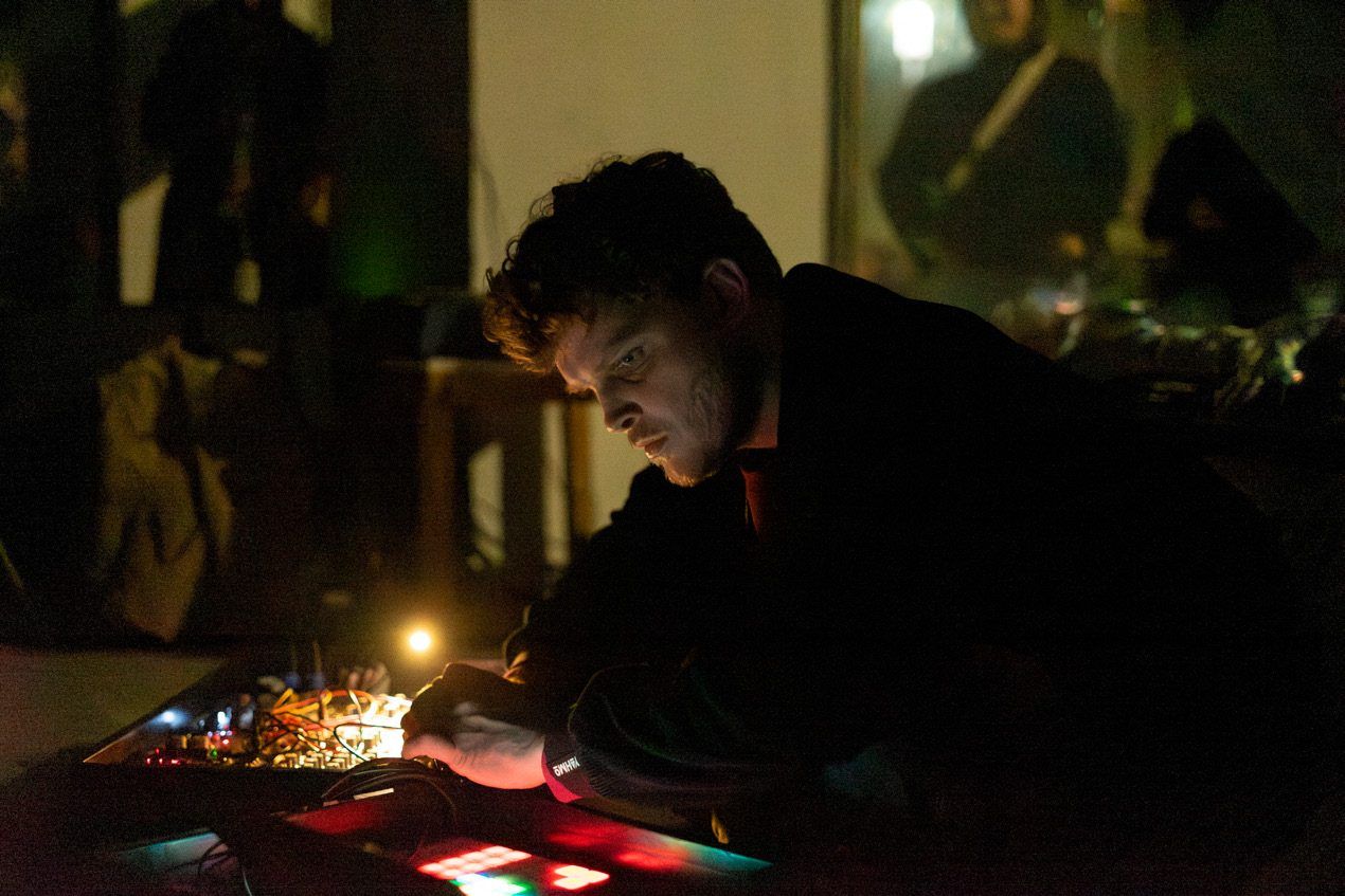 Elko Braas performing, leaning over mixer and controller