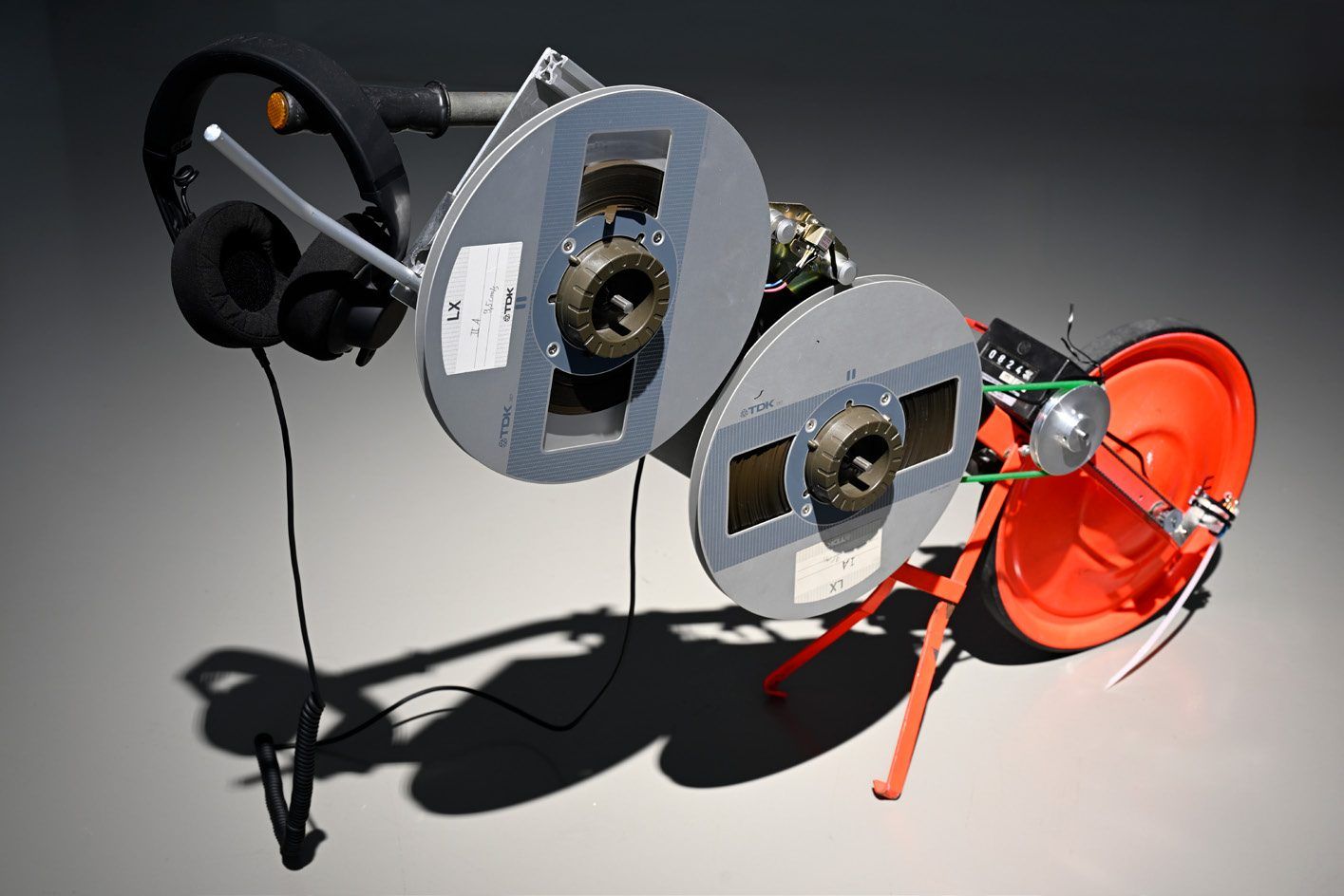 Surveying apparatus with tape reels, headphones and a red measuring wheel